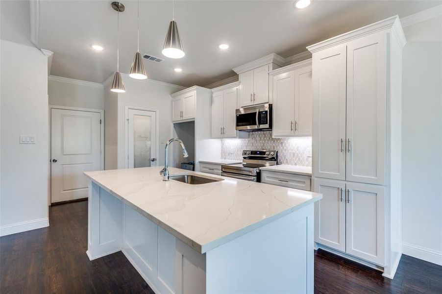 Kitchen featuring tasteful backsplash, an island with sink, sink, dark hardwood / wood-style floors, and appliances with stainless steel finishes