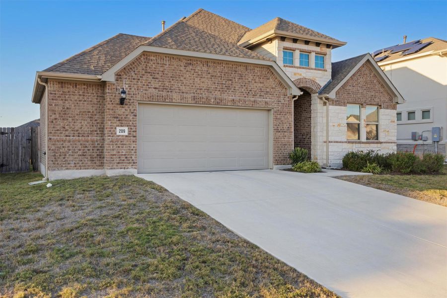 View of front of property featuring brick siding, driveway, a garage, and a shingled roof