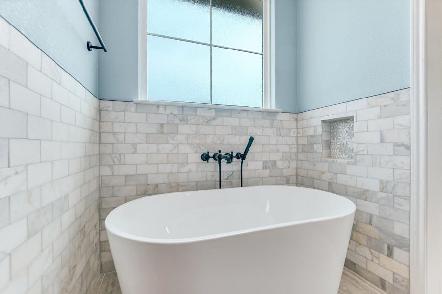 Bathroom with tile walls, a freestanding bath, and wainscoting