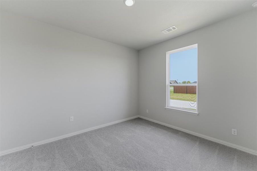 Carpeted room with a single window, light gray wall paint, white baseboards, and a ceiling light fixture Carpeted room with a single window, light gray wall paint, white baseboards, and a ceiling light fixture