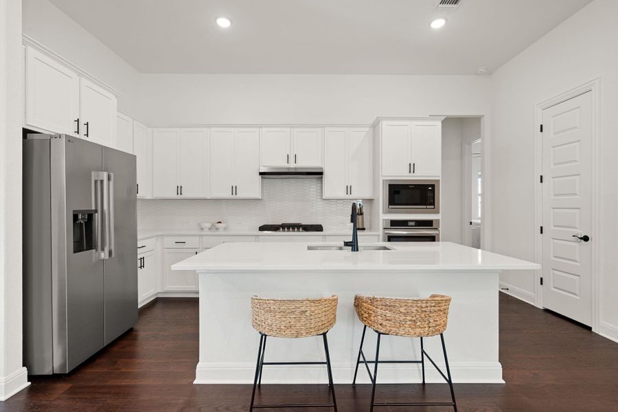 White cabinetry and dark flooring highlight this naturally culinary space. White cabinetry and dark flooring highlight this naturally culinary space.