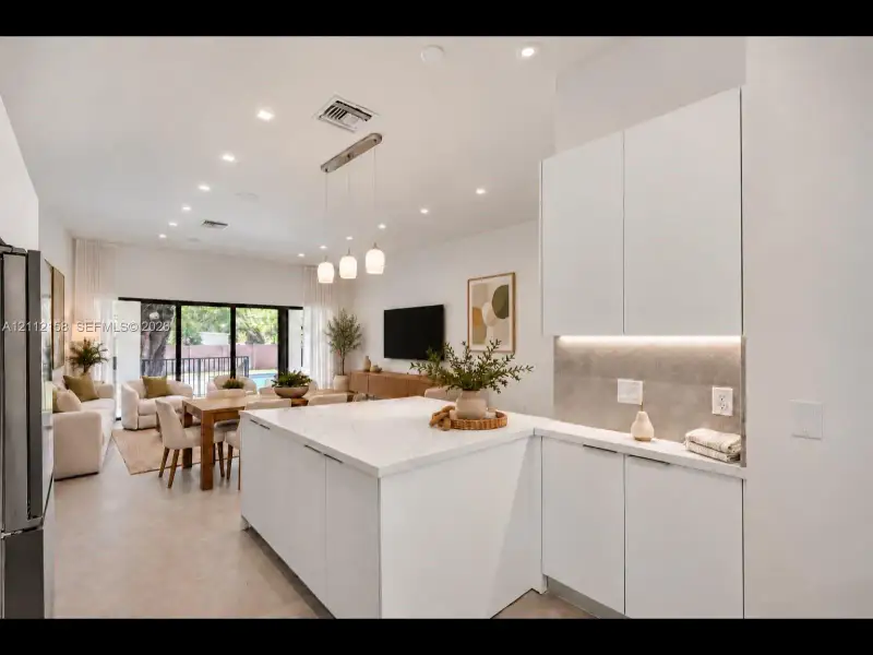 Chef-inspired kitchen with white cabinetry, under-cabinet lighting, and a designer pendant fixture