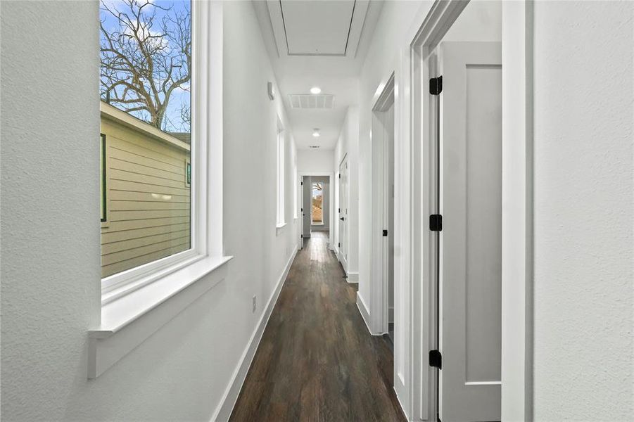 Hall featuring plenty of natural light, dark wood finished floors, attic access, a textured wall, and recessed lighting