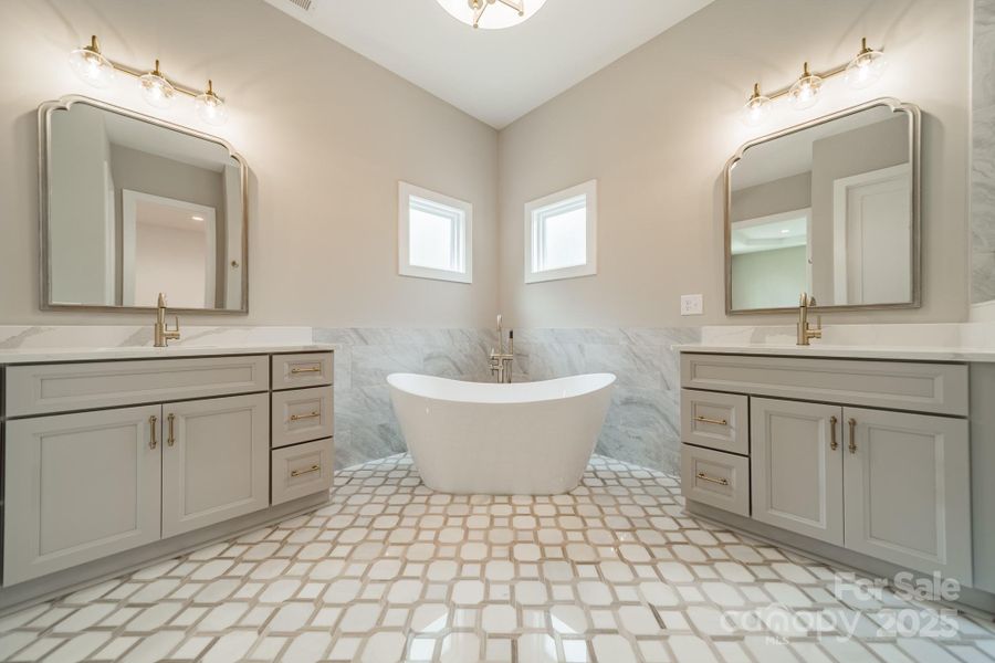 Your stunning Master Suite boasts beautiful custom lighting, cabinetry, tilework, a soaking tub, and a spacious shower.