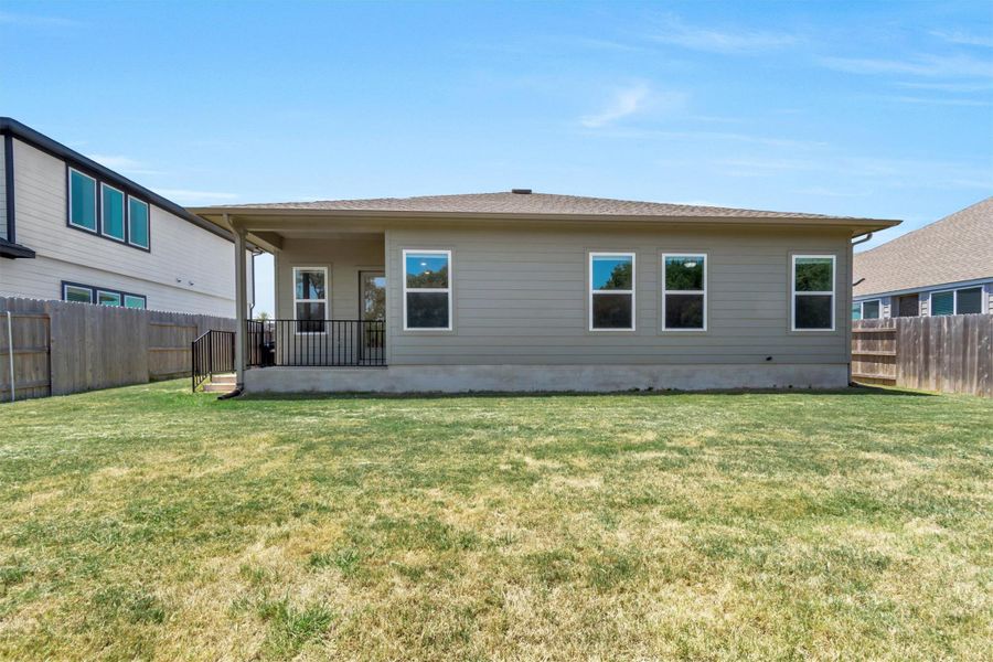 A modest backyard provides ample space for recreation behind a home with a small patio.