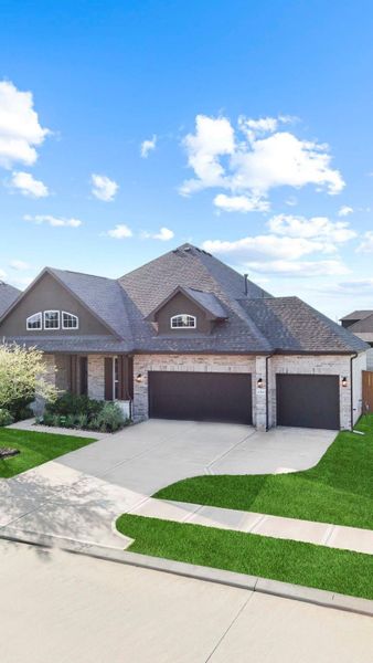 Front elevation view of the home with wide driveway and attractive brick-and-stone exterior.
