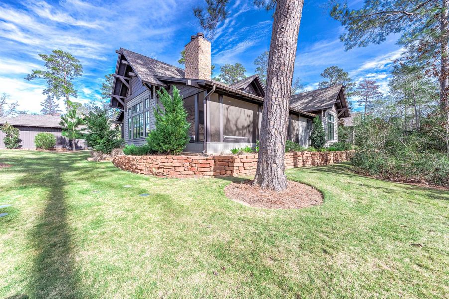 Screened In Back Porch with built out kitchen, furniture, and TV with nature views.