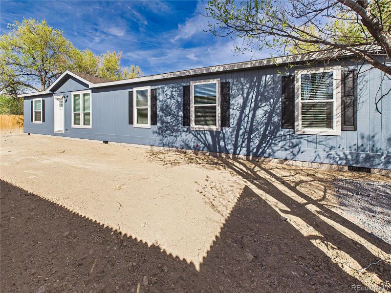 Long front elevation with ample yard space and natural shade from surrounding trees.