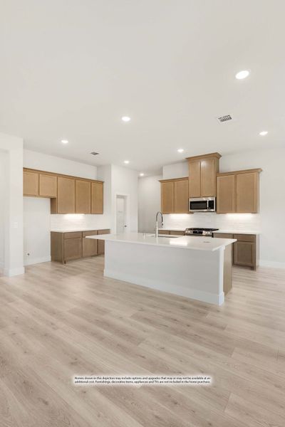Open kitchen with light wood cabinets, white island, stainless steel appliances, and light hardwood floors Open kitchen with light wood cabinets, white island, stainless steel appliances, and light hardwood floors