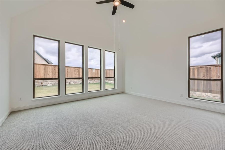 Empty room featuring a towering ceiling, carpet, and ceiling fan