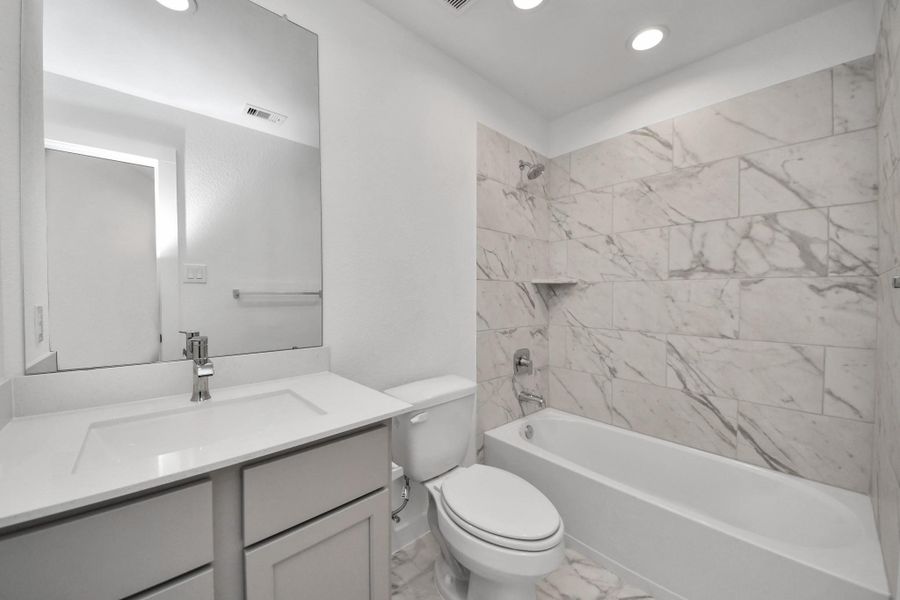 Secondary bath features tile flooring, bath/shower combo with tile surround, light stained wood cabinets, beautiful light countertop. Secondary bath features tile flooring, bath/shower combo with tile surround, light stained wood cabinets, beautiful light countertop.