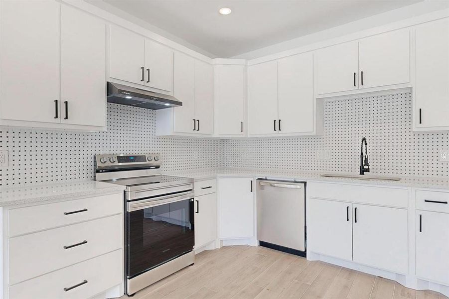 Kitchen featuring appliances with stainless steel finishes, tasteful backsplash, and white cabinets