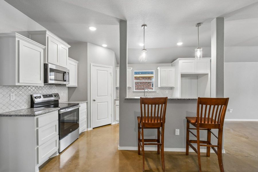 A well-appointed kitchen features stainless steel appliances, abundant cabinetry, and a granite-topped breakfast bar. A well-appointed kitchen features stainless steel appliances, abundant cabinetry, and a granite-topped breakfast bar.