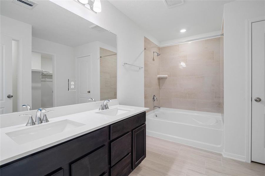 This primary bathroom is definitely move-in ready! Featuring an oversized tub/shower combo with tile surround, stained cabinets with light countertops, high ceilings, neutral paint, sleek and modern finishes.