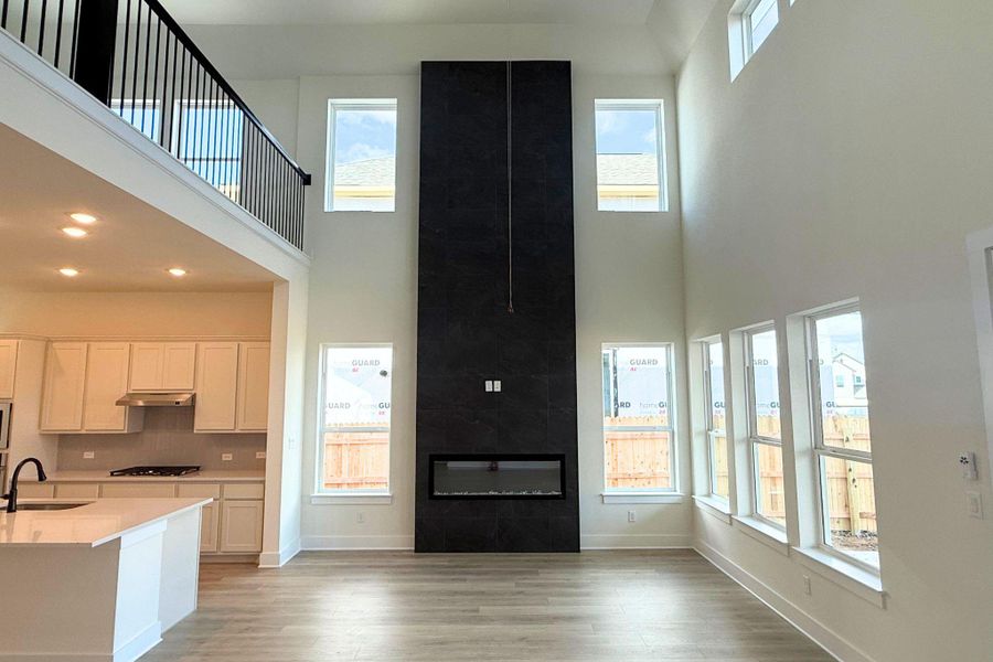 A spacious living area features high ceilings, a contemporary fireplace, and abundant natural illumination. A spacious living area features high ceilings, a contemporary fireplace, and abundant natural illumination.