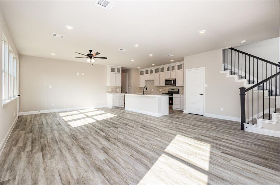 Unfurnished living room featuring stairs, light wood-type flooring, ceiling fan, and recessed lighting