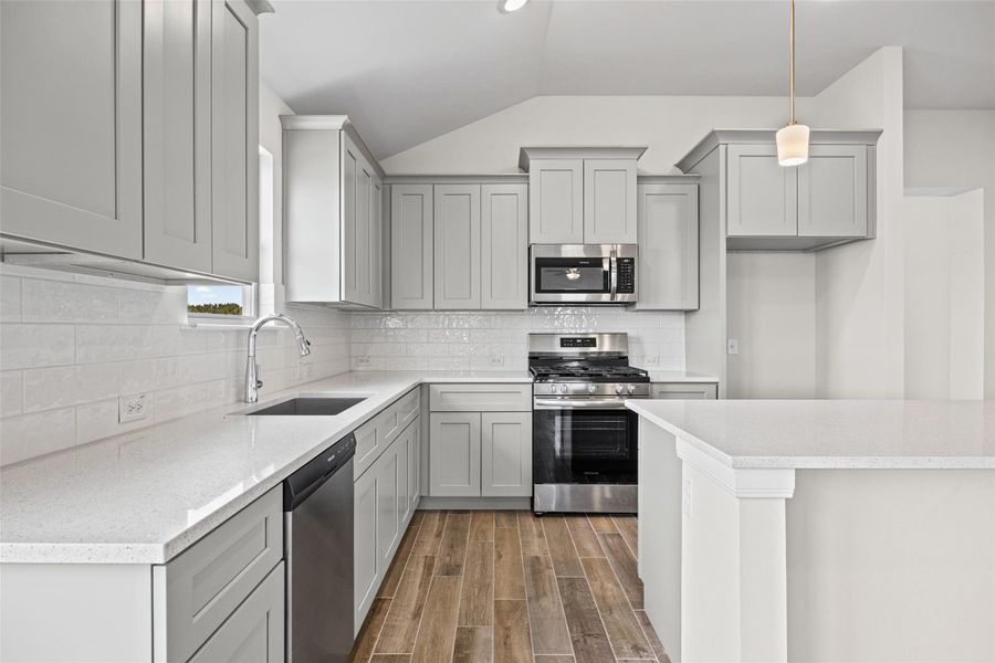 Streamlined cabinetry and pristine stone countertops define this modern kitchen with warm wood-look tile floors. Streamlined cabinetry and pristine stone countertops define this modern kitchen with warm wood-look tile floors.