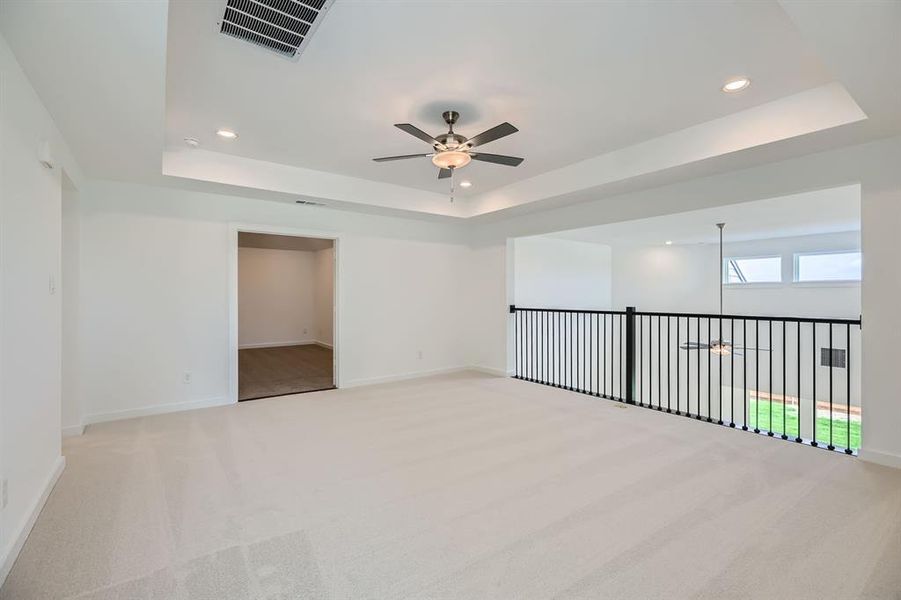 Spare room with a tray ceiling, a ceiling fan, light colored carpet, recessed lighting, and baseboards