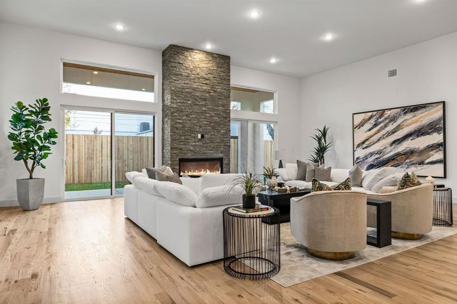 Living room with a stone fireplace and light hardwood / wood-style flooring