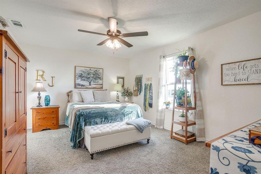 Primary bedroom featuring ceiling fan and a textured ceiling Primary bedroom featuring ceiling fan and a textured ceiling