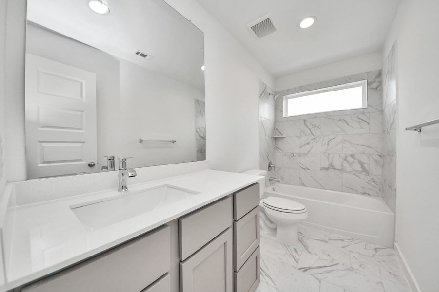 Secondary bath features tile flooring, bath/shower combo with tile surround, light stained wood cabinets, beautiful light countertop. Sample photo of completed home with similar floor plan. Actual colors and selections may vary. Secondary bath features tile flooring, bath/shower combo with tile surround, light stained wood cabinets, beautiful light countertop. Sample photo of completed home with similar floor plan. Actual colors and selections may vary.