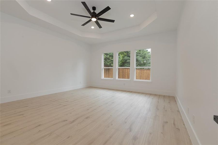 Spare room featuring a raised ceiling, light wood finished floors, recessed lighting, and a ceiling fan