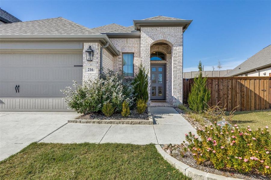 View of front of property featuring brick siding, an attached garage, stone siding, and concrete driveway