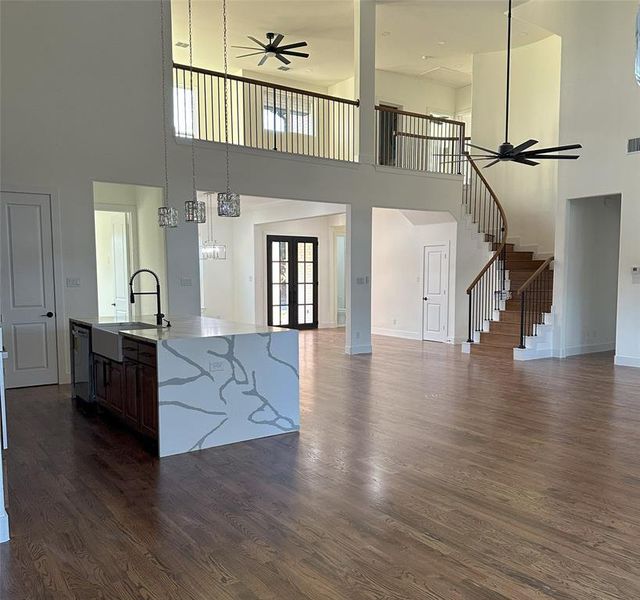 Unfurnished living room featuring dark hardwood / wood-style flooring, sink, ceiling fan, and french doors