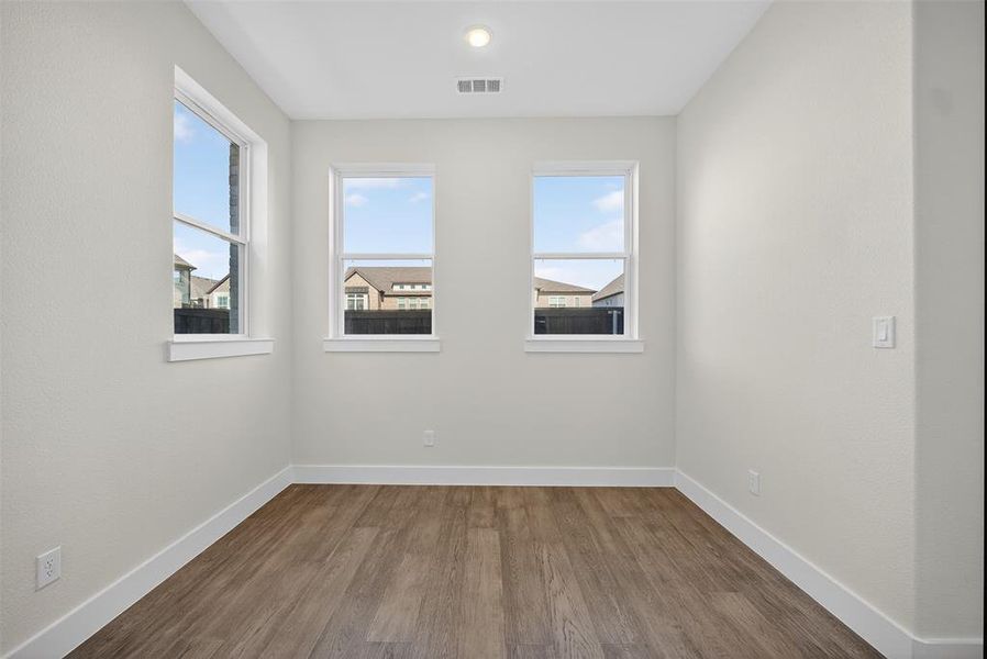 Spare room with dark wood-style flooring and healthy amount of natural light Spare room with dark wood-style flooring and healthy amount of natural light