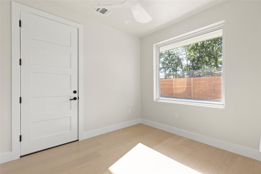 Natural light pours across the light wood flooring through a large picture window.