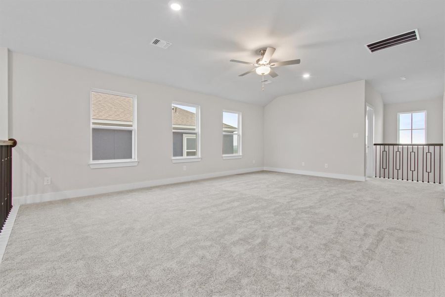 Carpeted empty room with vaulted ceiling and ceiling fan