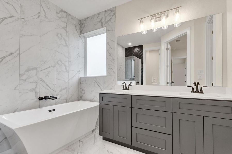 Marble-clad walls and flooring enhance this tranquil primary bath, complete with a freestanding soaking tub.