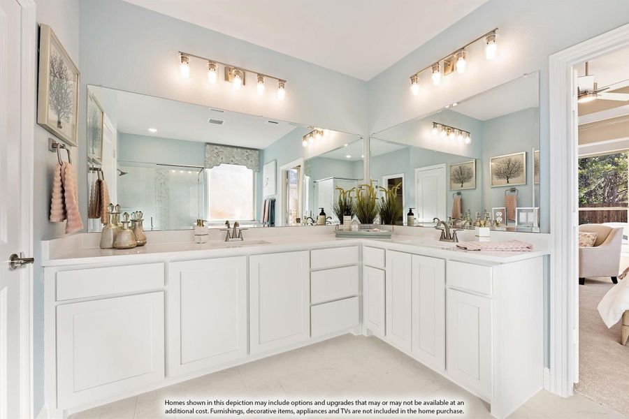Master bathroom with double vanity, white cabinets, large mirrors, and light blue walls open to bedroom