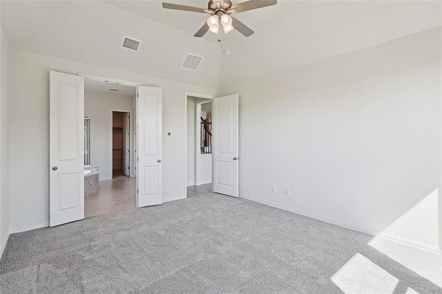 Unfurnished bedroom featuring ceiling fan, light carpet, and high vaulted ceiling