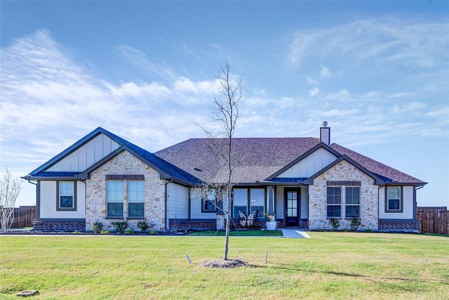 Craftsman inspired home featuring board and batten siding, stone siding, a chimney, and roof with shingles