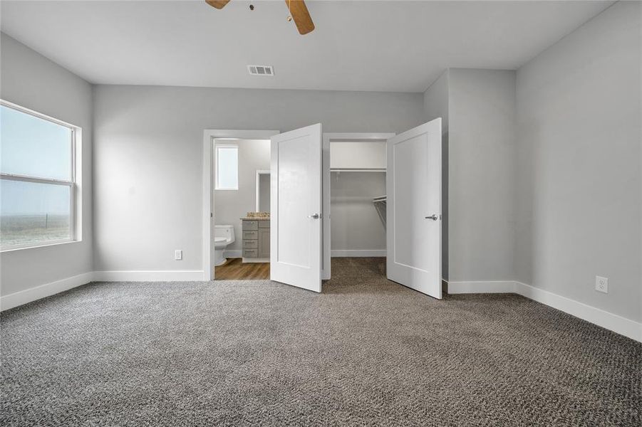 Unfurnished bedroom featuring ensuite bathroom, carpet, a spacious closet, ceiling fan, and a closet