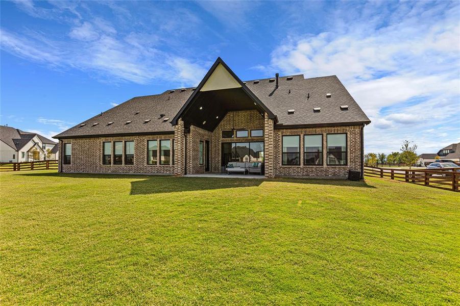Rear view of property featuring a fenced backyard, a patio, brick siding, a shingled roof, and an outdoor living space