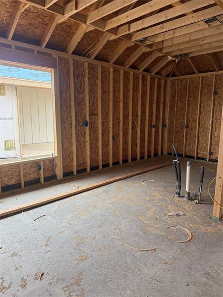 Unfinished interior space featuring exposed wood framing, an open ceiling with visible joists, and a concrete floor