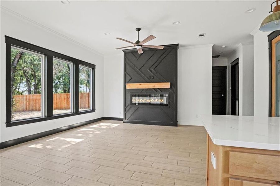 Unfurnished living room with a fireplace, ornamental molding, wood tiled floors, recessed lighting, and a ceiling fan