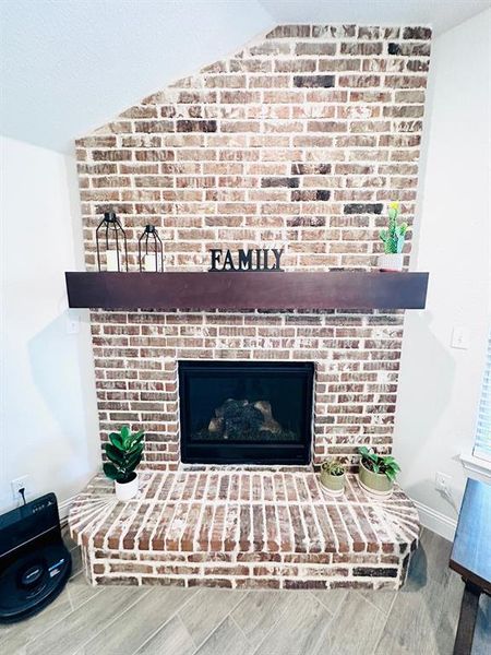 Room details featuring a brick fireplace and hardwood / wood-style flooring