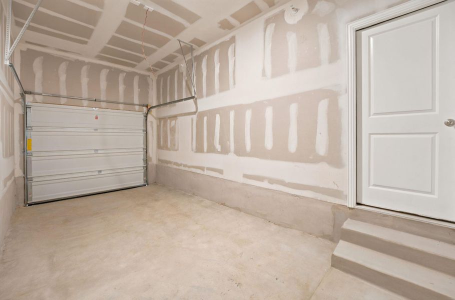 A spacious one car garage features concrete flooring and drywall ready for customization.