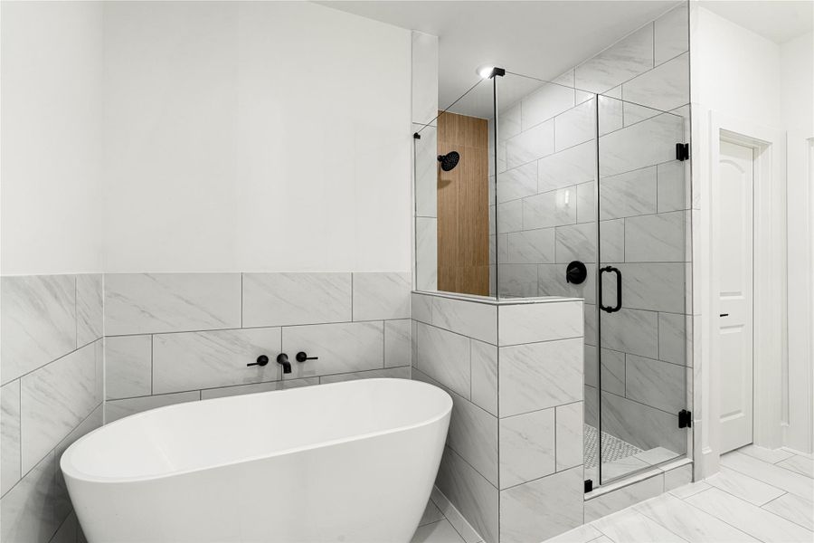 Sleek freestanding bathtub and a spacious glass-enclosed shower. The white and gray tile work enhances the clean, contemporary aesthetic.