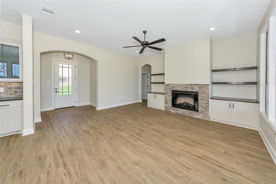 Unfurnished living room with a fireplace, light wood-type flooring, and ceiling fan