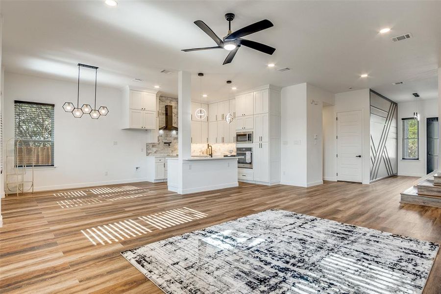 Unfurnished living room with light wood finished floors, a ceiling fan, recessed lighting, and a chandelier