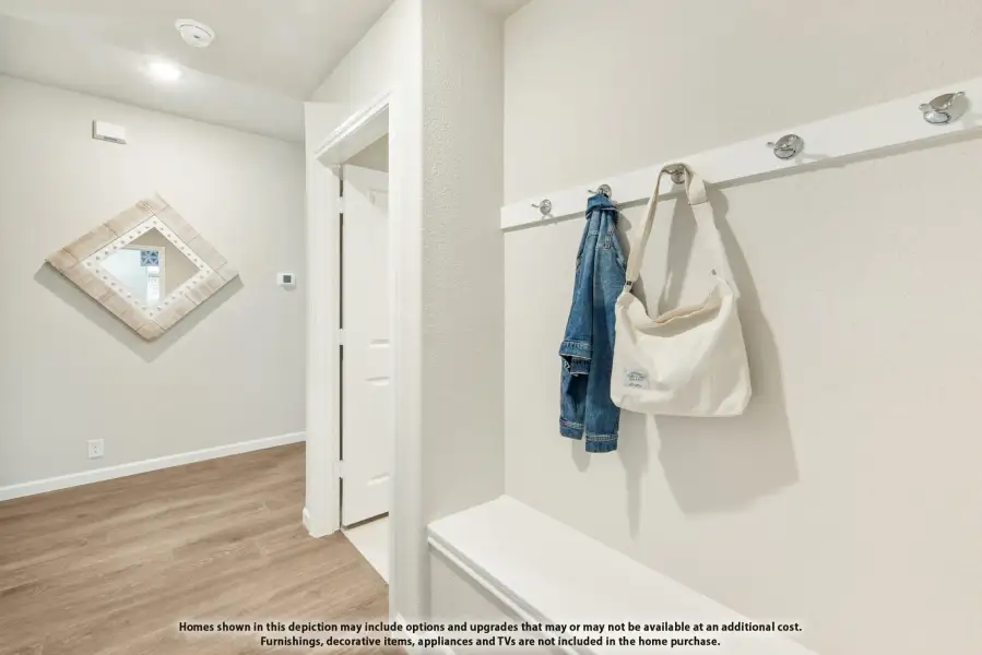 Mudroom entryway with wall-mounted coat hooks, built-in bench, and light wood floors