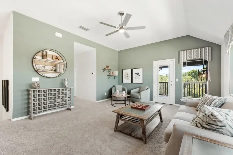 Living room with vaulted ceiling, ceiling fan, green walls, carpet flooring, and door to outdoor balcony