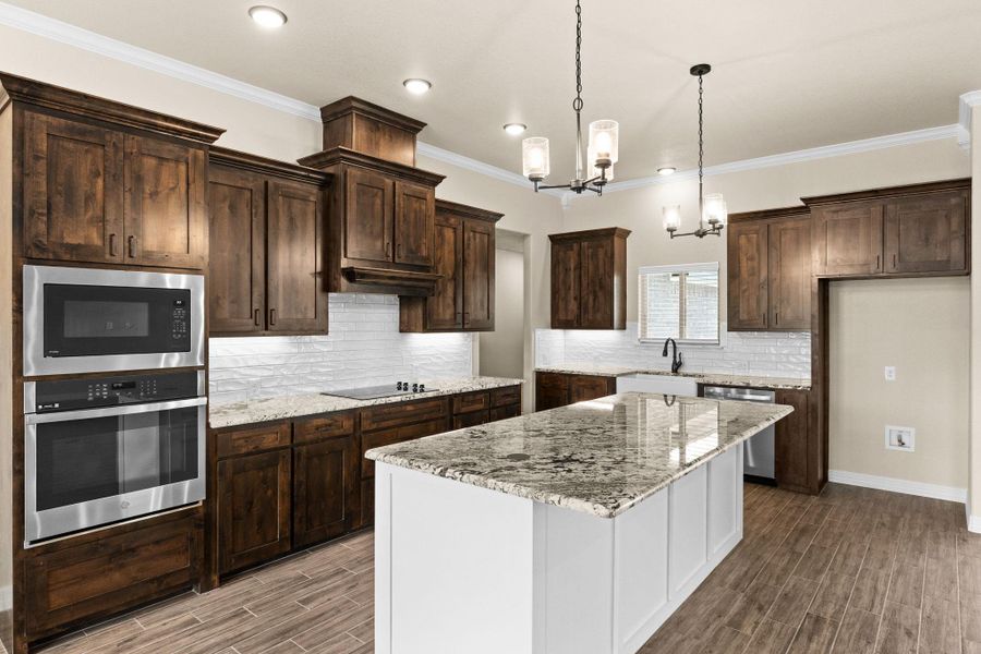 Kitchen featuring crown molding, hanging light fixtures, backsplash, granite countertops, and recessed lighting Kitchen featuring crown molding, hanging light fixtures, backsplash, granite countertops, and recessed lighting