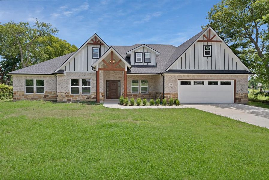 View of front of property featuring a front yard, board and batten siding, a shingled roof, and a garage