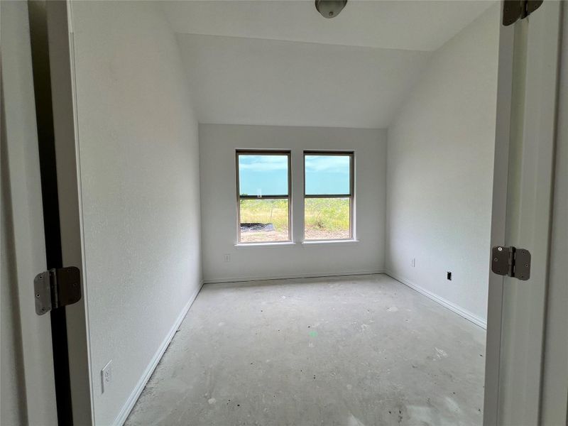 Unfurnished room featuring lofted ceiling and unfinished concrete flooring