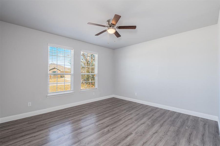 Spare room with ceiling fan, wood finished floors, and baseboards